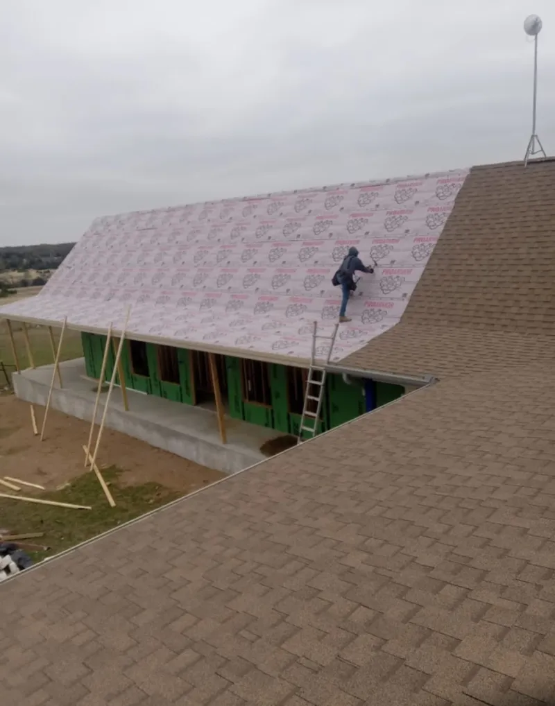 Worker preparing underlayment for a metal roof installation in Carrollton